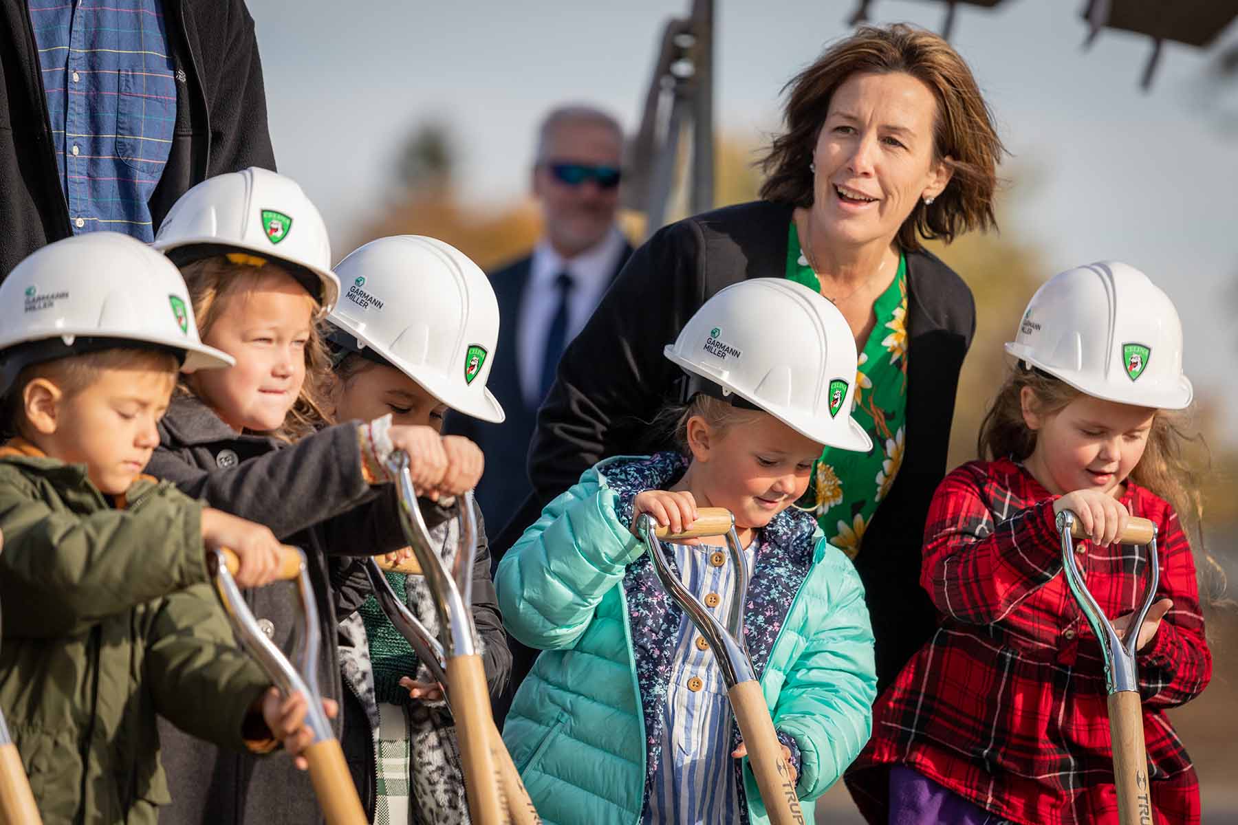 Garmann Miller team with kids wearing hard hats and shovels